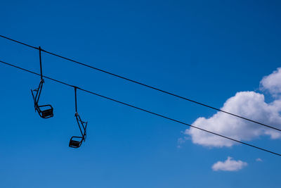 Low angle view of ski lifts against blue sky