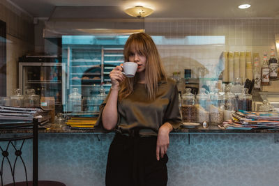 Full length of a young woman drinking coffee