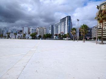 Empty road by buildings against sky in city