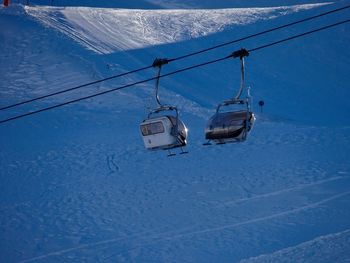 Overhead cable car on snow covered landscape against sky