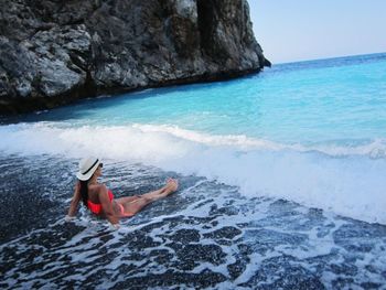 Full length of woman relaxing on shore at beach