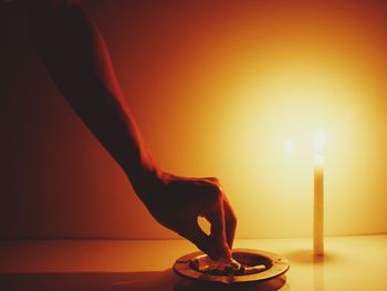 Close-up of hand holding lit candle