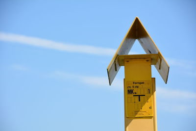 Low angle view of yellow sign against sky