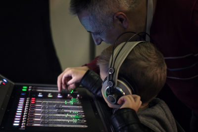 Music teacher helping boy to learn sound mixing in recording studio