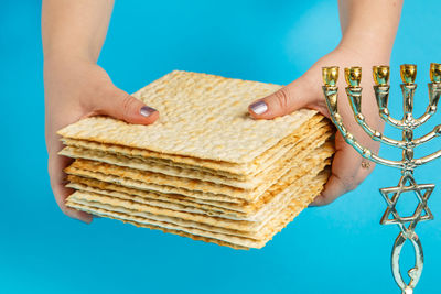 Close-up of woman hand holding stack against blue background