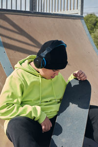 Boy with skateboard sitting outdoors