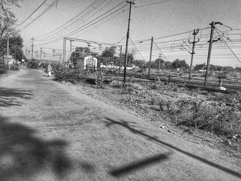 Railroad tracks by road against sky