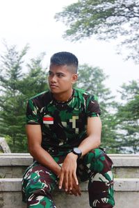 Army soldier looking away while sitting outdoors
