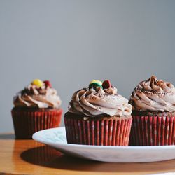 Close-up of cupcakes served in plate on table against wall