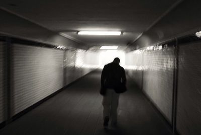 Rear view of woman walking in tunnel