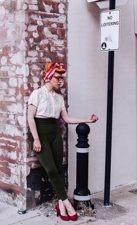 Beautiful woman standing on bollard on footpath at city