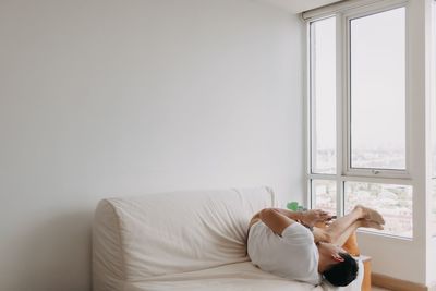 Rear view of woman sitting on bed at home