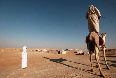 People riding horse in desert against sky