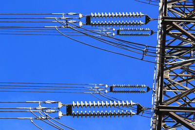 Low angle view of electricity pylon against blue sky