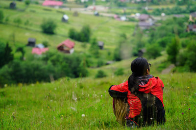 Rear view of woman sitting on grassy field