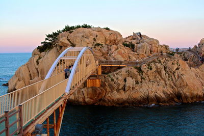 Footbridge over sea by rock formation