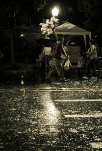 People sitting on wet street during rainy season at night