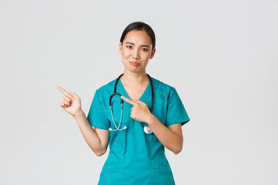 Portrait of young woman standing against white background