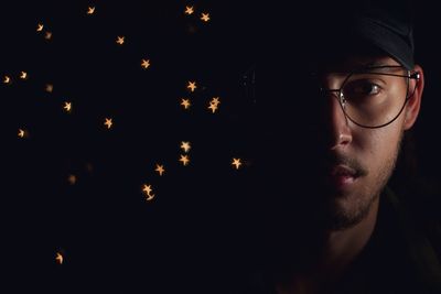 Close-up portrait of young man by star shapes against black background