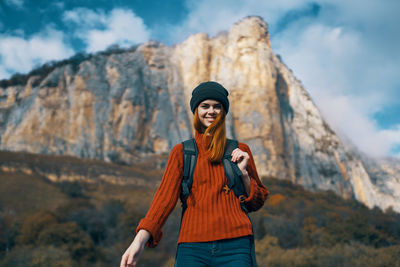 Portrait of smiling young woman standing on rock