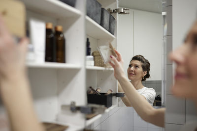 Woman putting standing in front of open cupboard