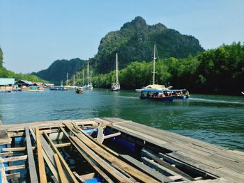 Boats moored on river by mountains against clear sky