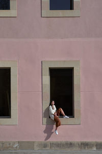 Side view of woman standing against building