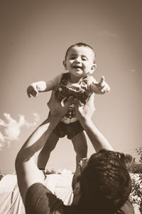 Full length of happy girl holding camera against sky