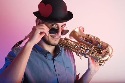 Midsection of man wearing hat holding saxophone