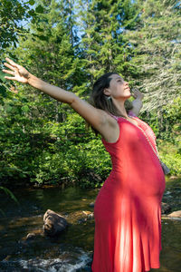 Side view of young woman standing against trees