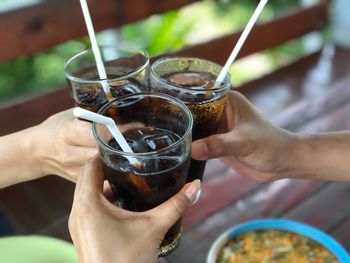 Cropped hands of friends toasting cold drinks at restaurant