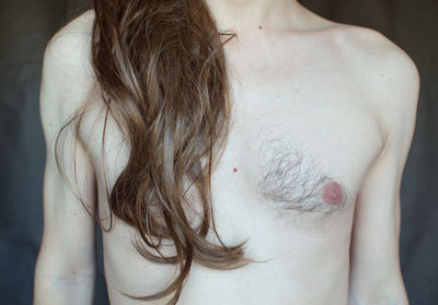 Midsection of shirtless man with long hair standing