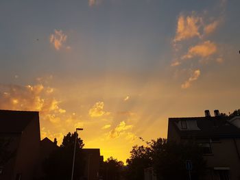 Low angle view of silhouette houses against sky at sunset