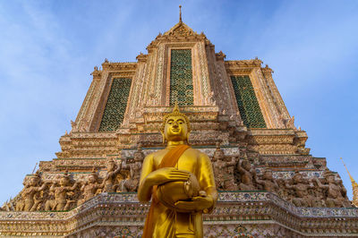 Low angle view of statue against temple building against sky