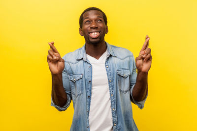 Portrait of young man standing against yellow background