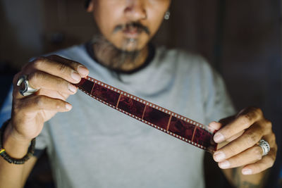 Midsection of man holding film reel