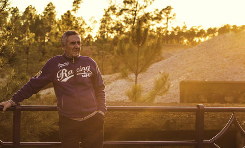 Portrait of smiling man standing against railing