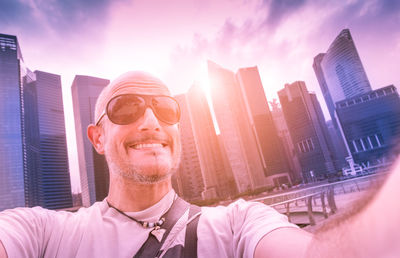 Portrait of smiling mid adult man against modern buildings in city