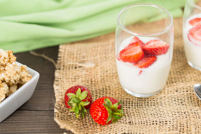 Strawberries and milk in glass on jute