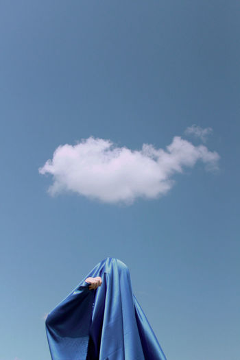 Low angle view of woman wearing scarf standing against sky