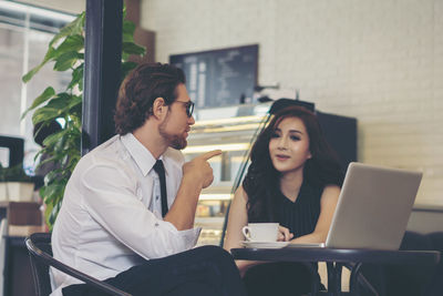 Business colleagues using laptop while sitting at table in cafe