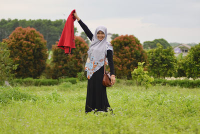 Portrait of smiling woman in hijab standing on field 