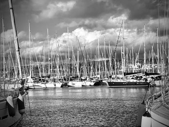 Sailboats moored at harbor against sky