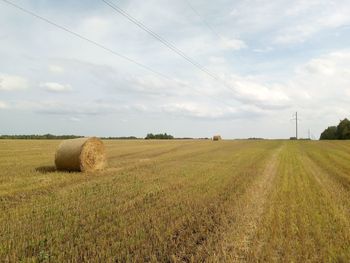 Hay bales on field against sky