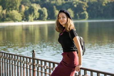 Portrait of young woman standing against lake