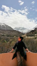 Rear view of man standing on mountain against sky