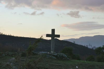 Cross on cemetery against sky during sunset