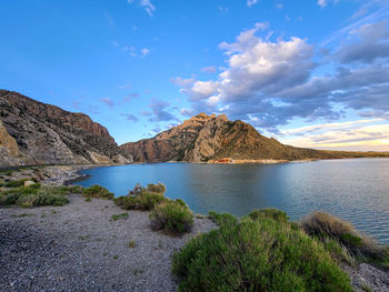 Scenic view of lake by mountains against blue sky