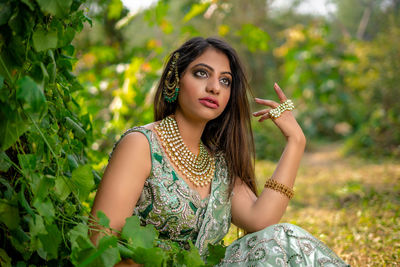 Portrait of young woman standing against plants