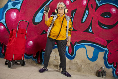 Full length portrait of woman standing against graffiti